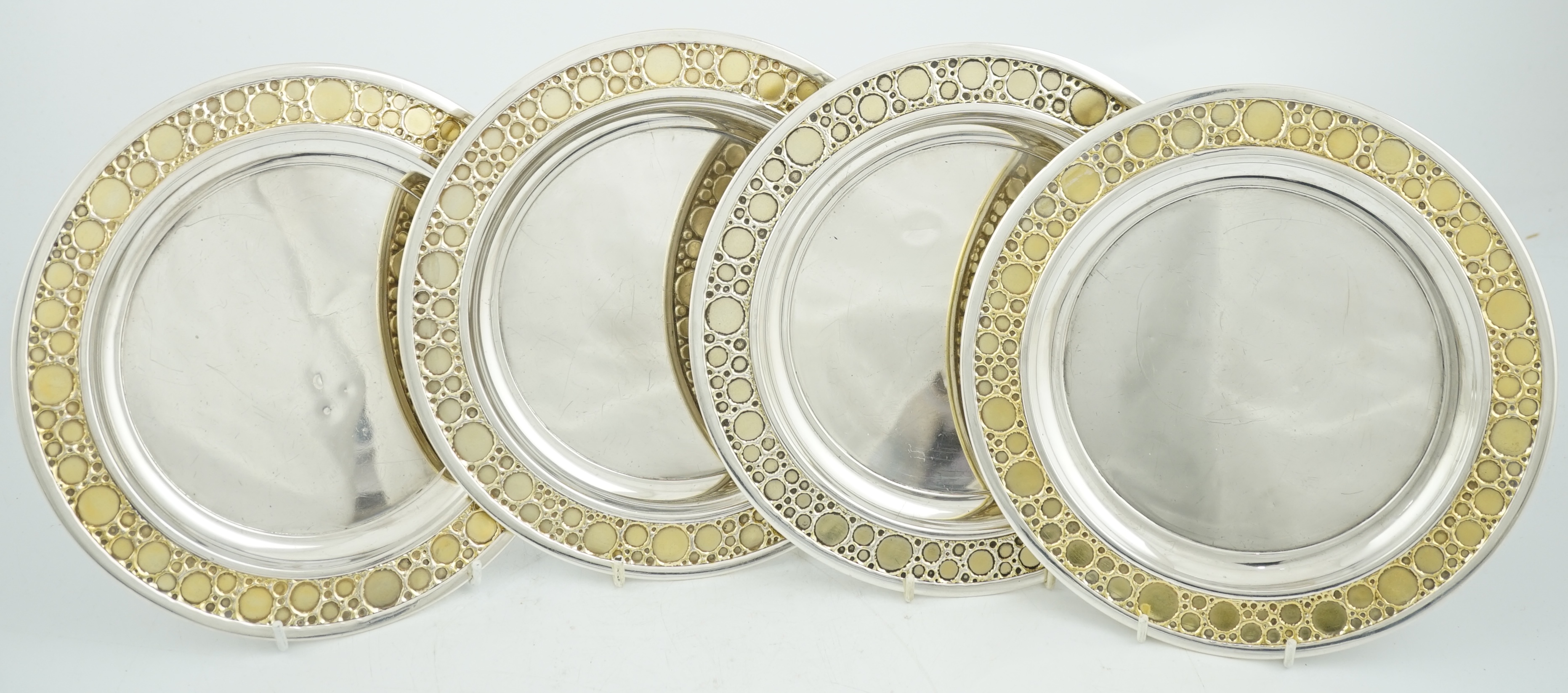 A set of four Elizabeth II Stuart Devlin parcel gilt silver circular plates